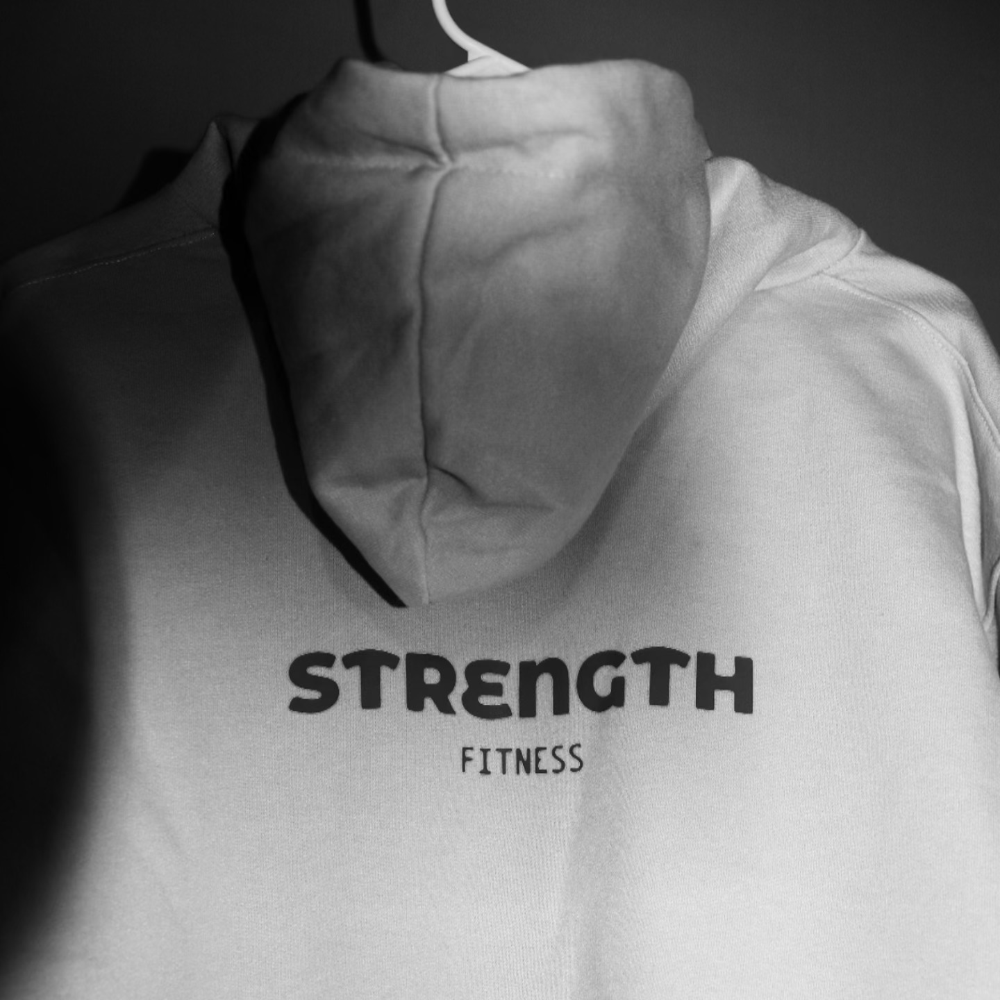 Detalle de la sudadera con letras Strength Fitness en fotografía blanco y negro